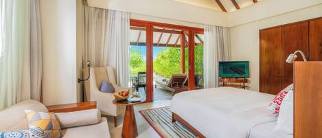 A hotel room with a bed, a sofa, a TV, and a view of the outdoors.