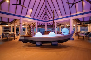 A boat-shaped room with a high ceiling, wooden beams, and large windows.