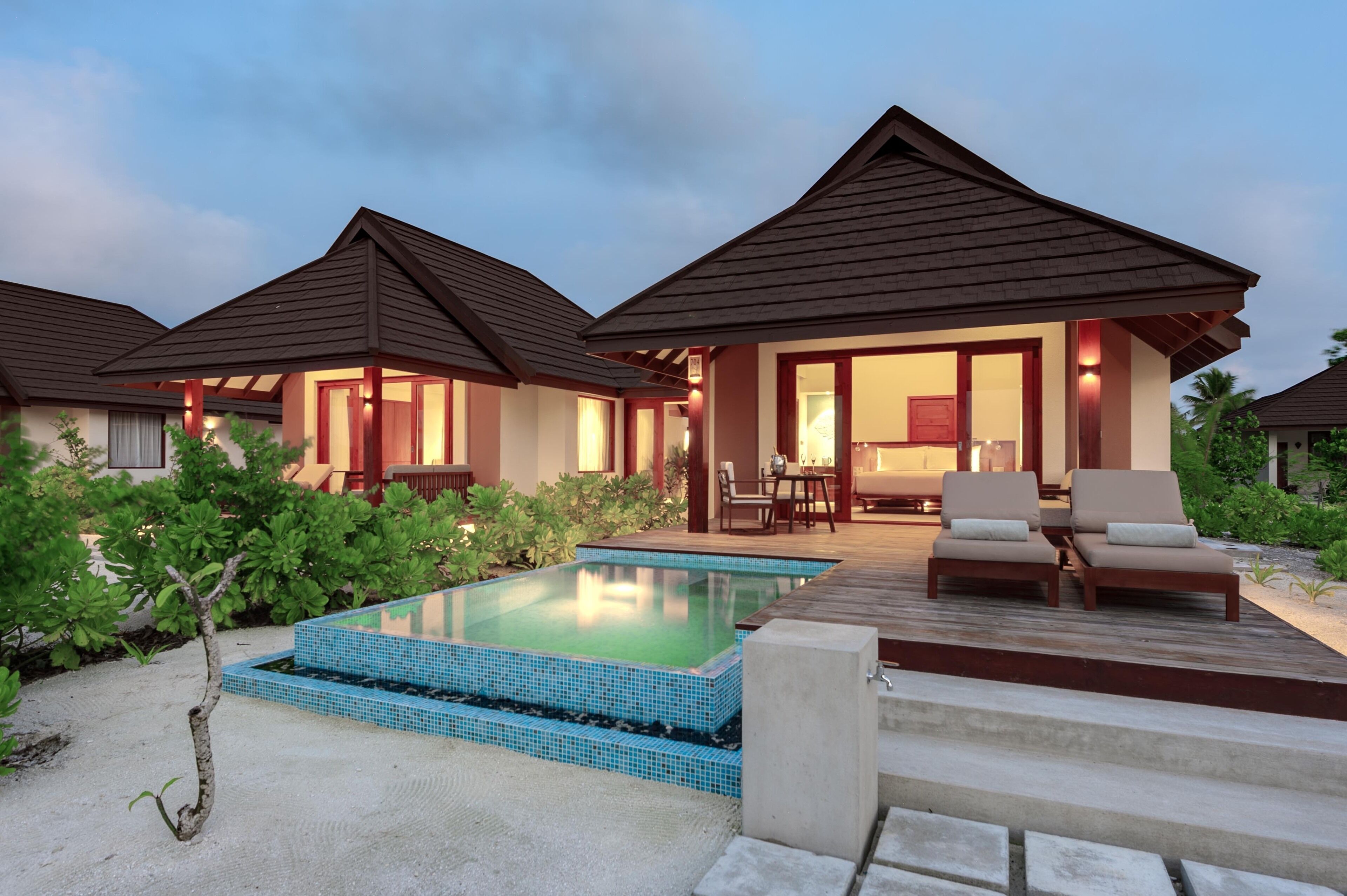 Un resort con piscina, mobiliario exterior y varias habitaciones para huéspedes.