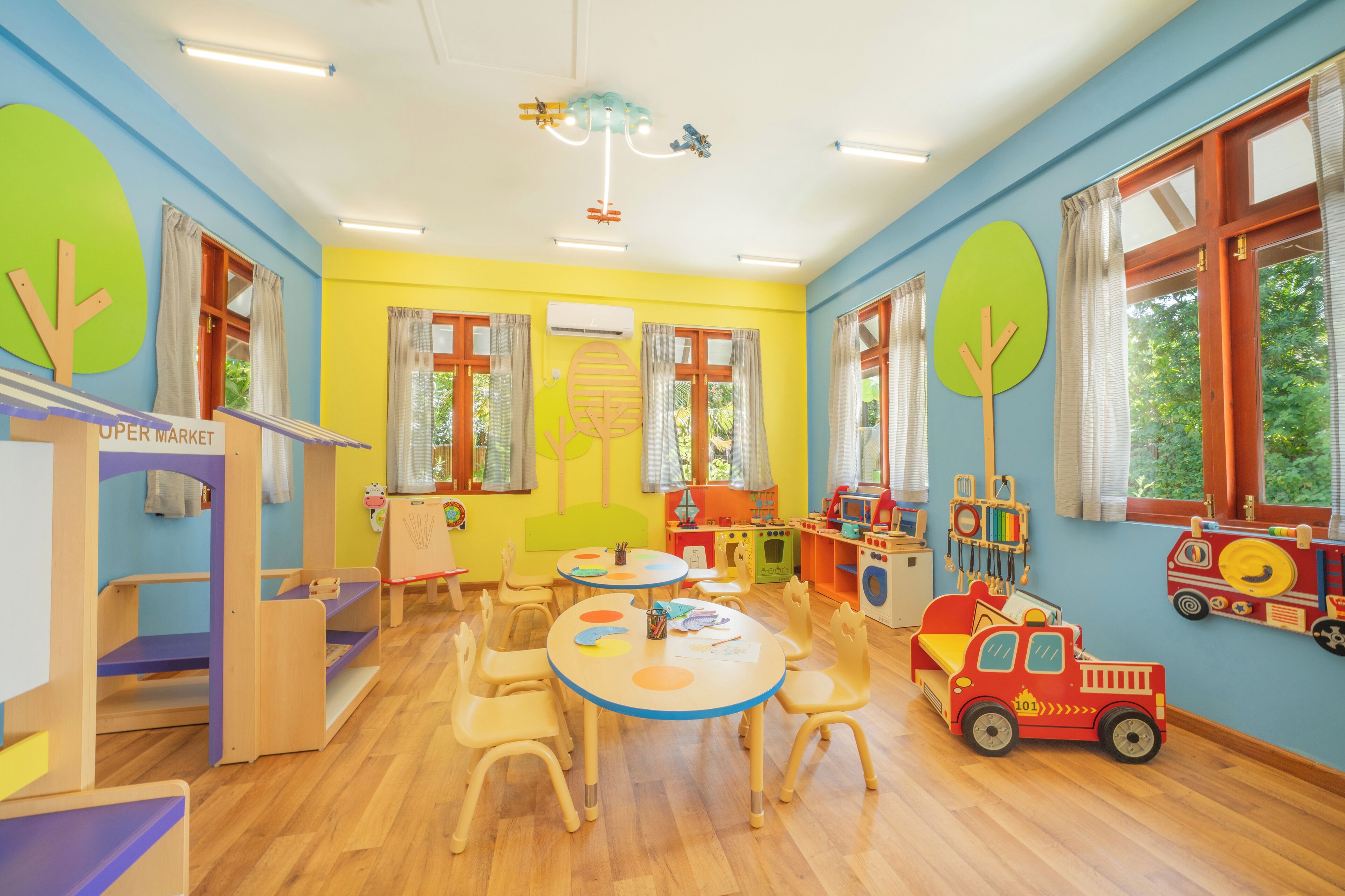 Un salón de juegos infantil de colores vivos, con una mesa, sillas y juguetes educativos.