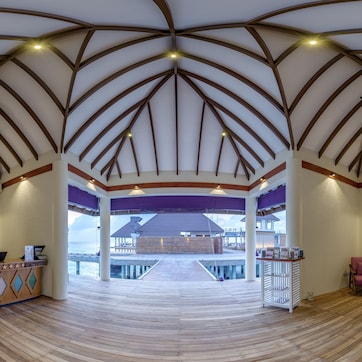A spacious lobby with a high wooden ceiling, a reception desk, and seating area.