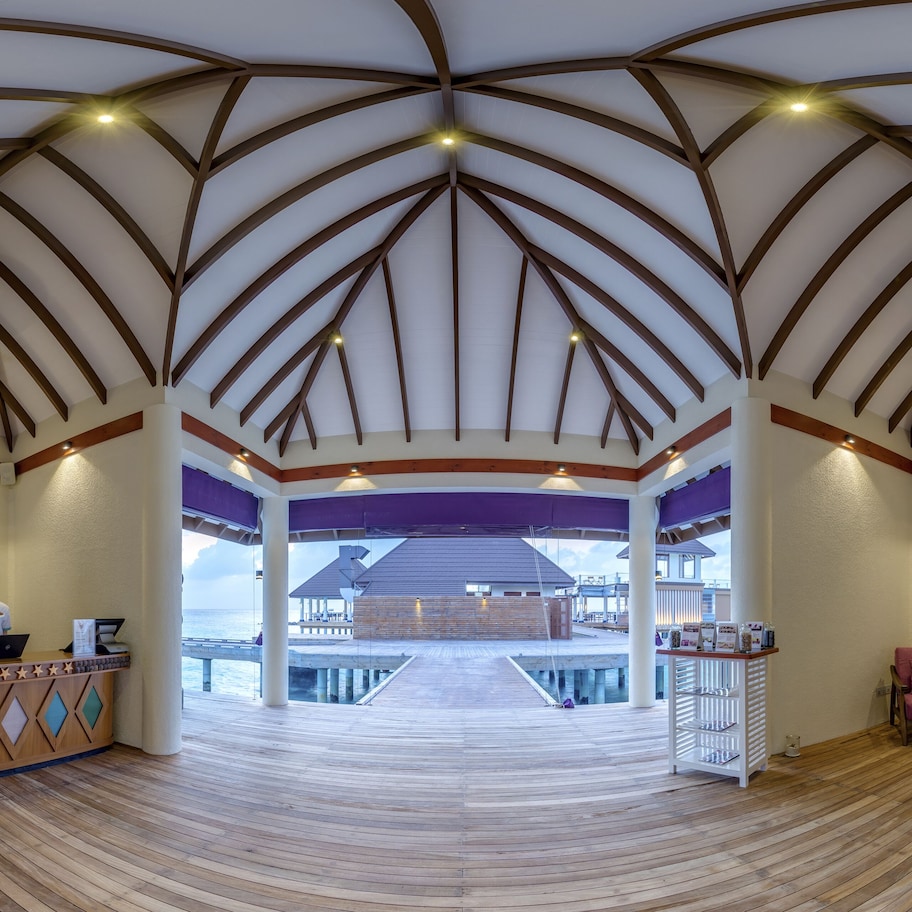 A spacious lobby with a high wooden ceiling, a reception desk, and seating area.