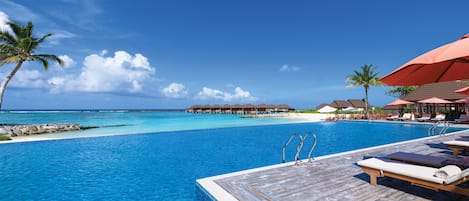 Una piscina al aire libre, sombrillas, sillones reclinables de piscina