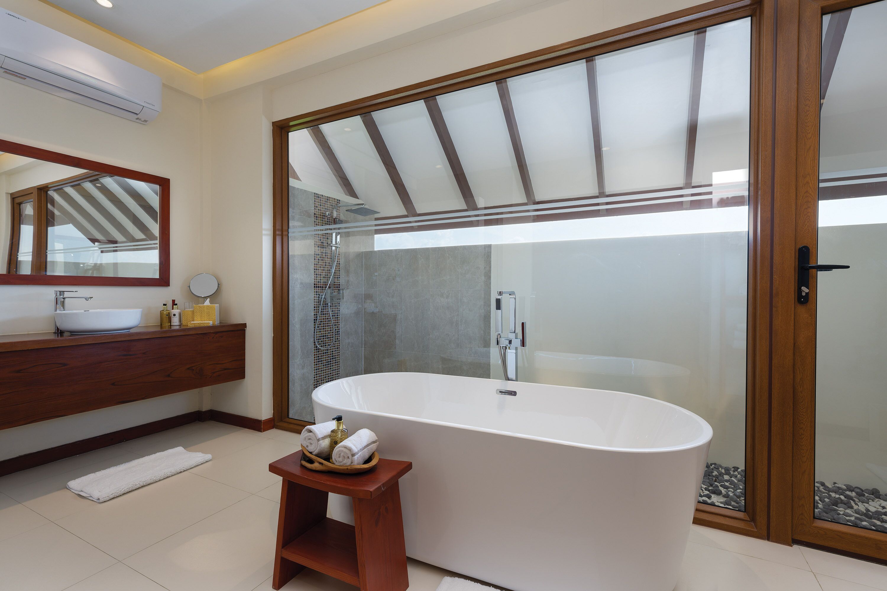 A modern bathroom with a freestanding bathtub, a wooden vanity, and a large mirror.