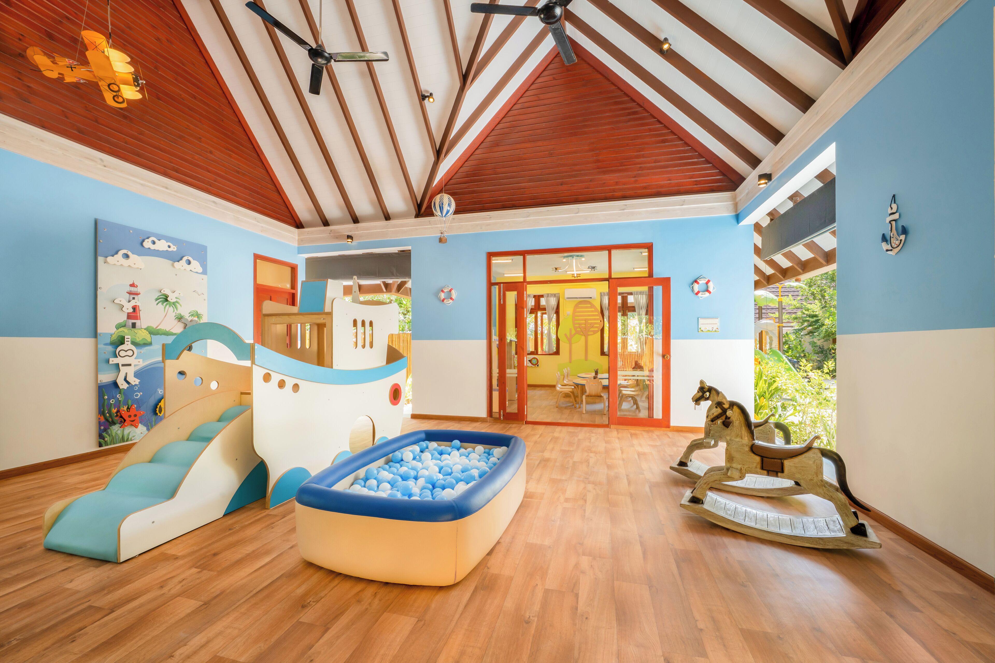 Ein Spielbereich für Kinder mit Rutsche, aufblasbarem Pool und Schaukelpferd.