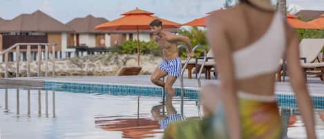 Une piscine à l’eau d’un bleu limpide, entourée de chaises longues et de parasols.
