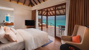 A bedroom with a large bed, a TV, and a view of the ocean.
