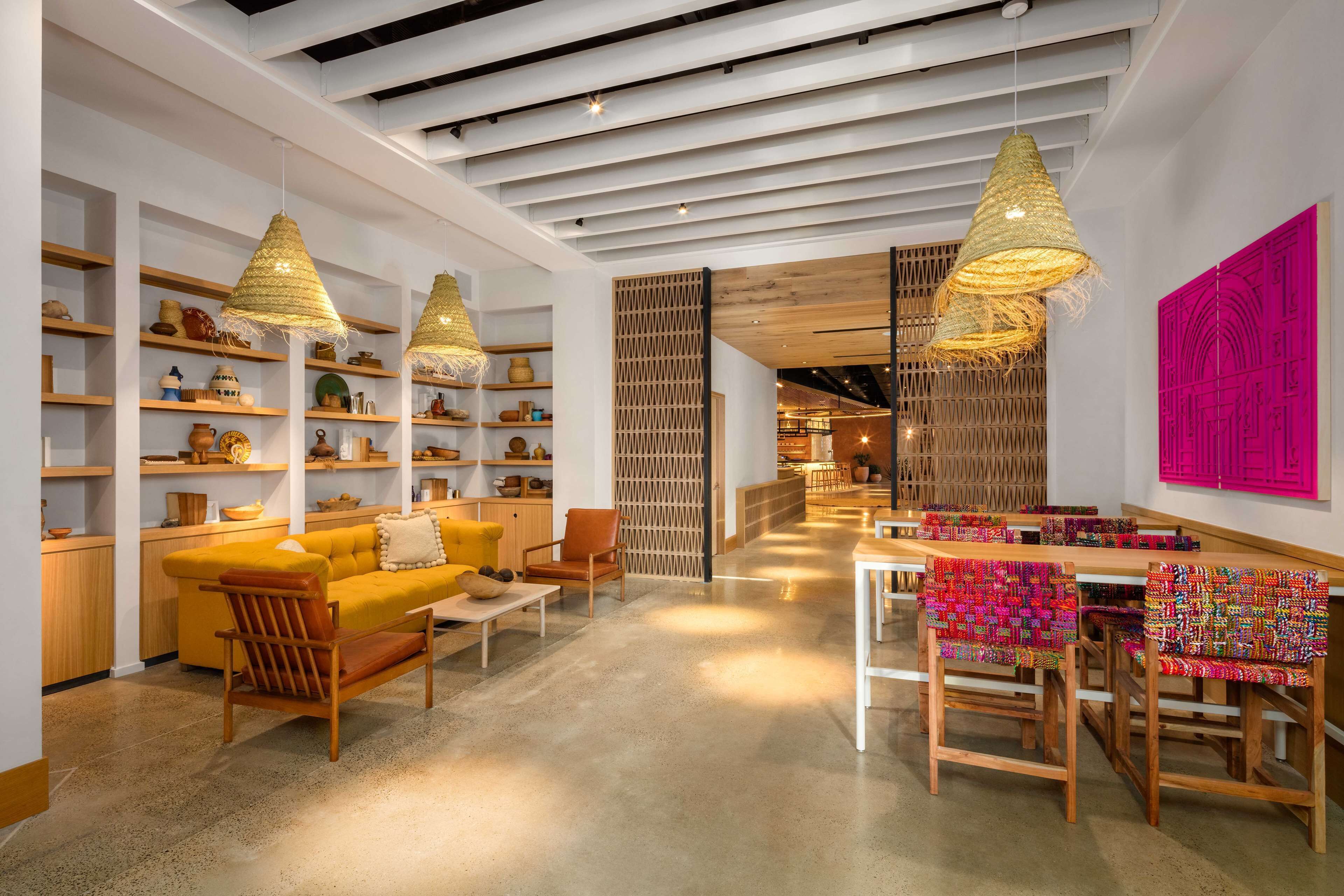 A modern interior with wooden furniture, shelves with pottery, and a bright pink wall.