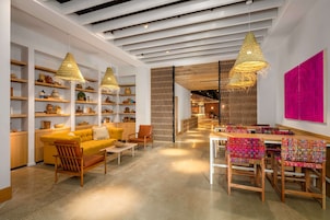 A modern interior with wooden furniture, shelves with pottery, and a bright pink wall.