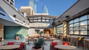 A rooftop bar with outdoor seating, large windows, and a view of the city skyline. - Motto by Hilton Philadelphia Rittenhouse Square (Philadelphia)