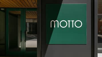 Un letrero verde con la palabra 'MOTTO' en una pared.