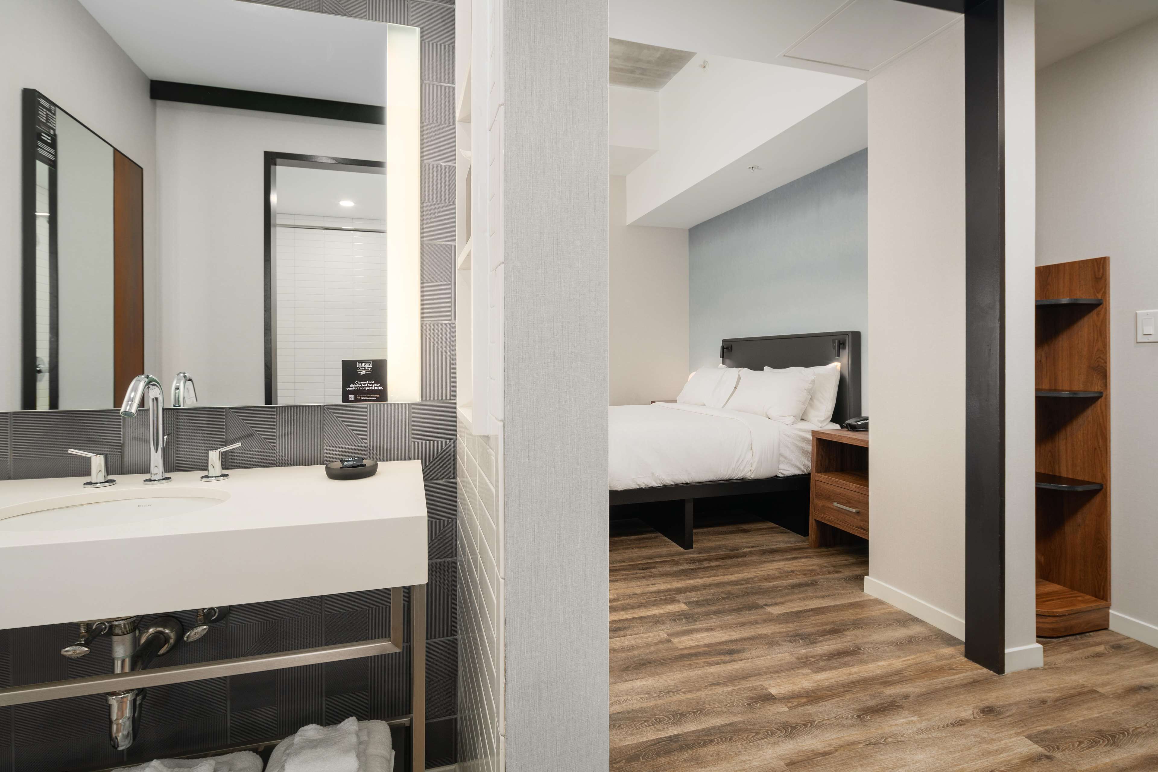A modern bathroom with a large mirror, a white sink, and a dark vanity.
