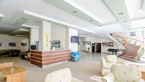 A spacious lobby with a reception desk, seating area, and a staircase leading to upper floors. - International House of Journalists (Varna)