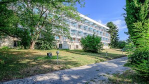 A multi-story building with balconies, surrounded by trees and a pathway. - International House of Journalists (Varna)