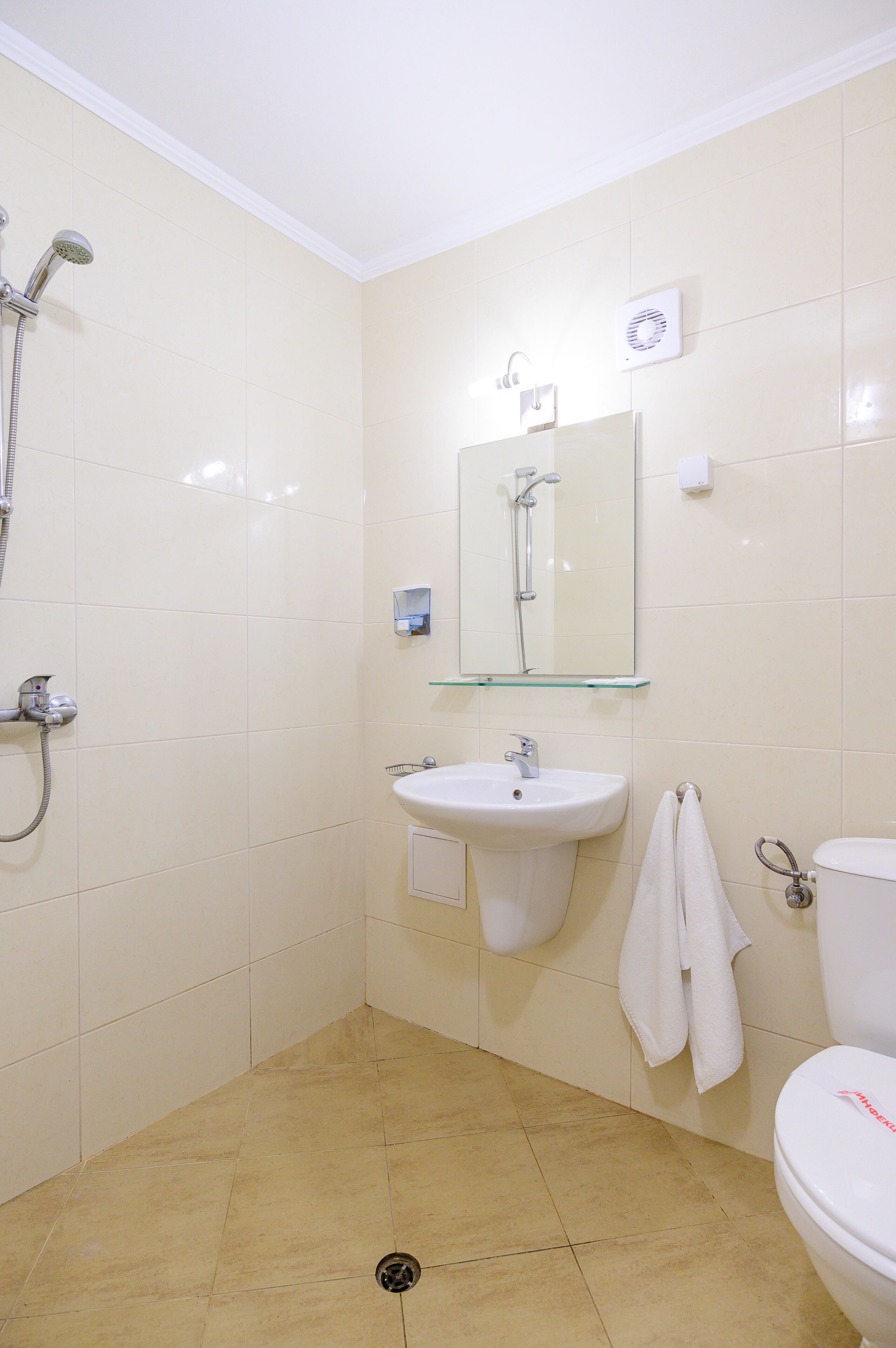 Un baño con ducha, lavamanos, espejo e inodoro.