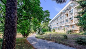 A pathway leading to a multi-story building with balconies, surrounded by trees and greenery. - International House of Journalists (Varna)