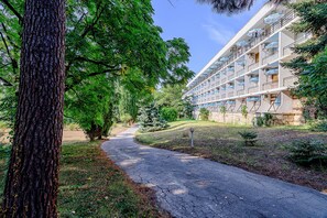 A pathway leading to a multi-story building with balconies, surrounded by trees and greenery. - International House of Journalists (Varna)