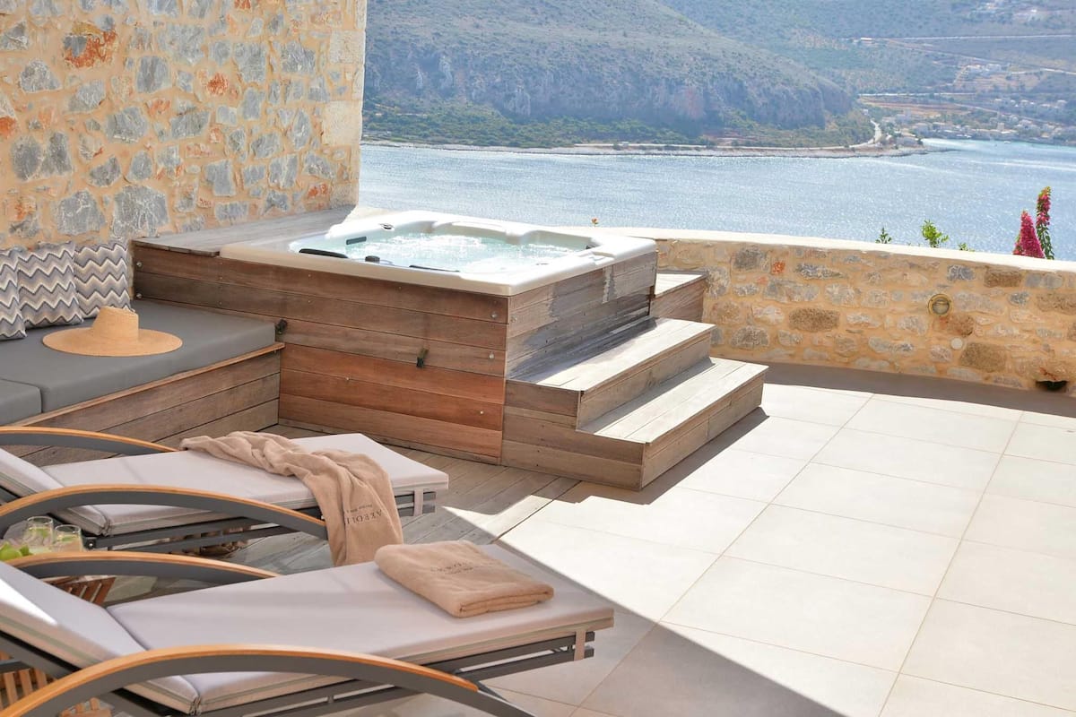 Un área de spa con un jacuzzi, sillones de descanso y una pared de piedra.