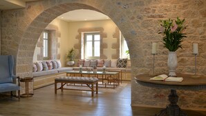 Un salón amplio con un arco de piedra, un conjunto de sofás, una mesita de centro y un jarrón decorativo con flores.