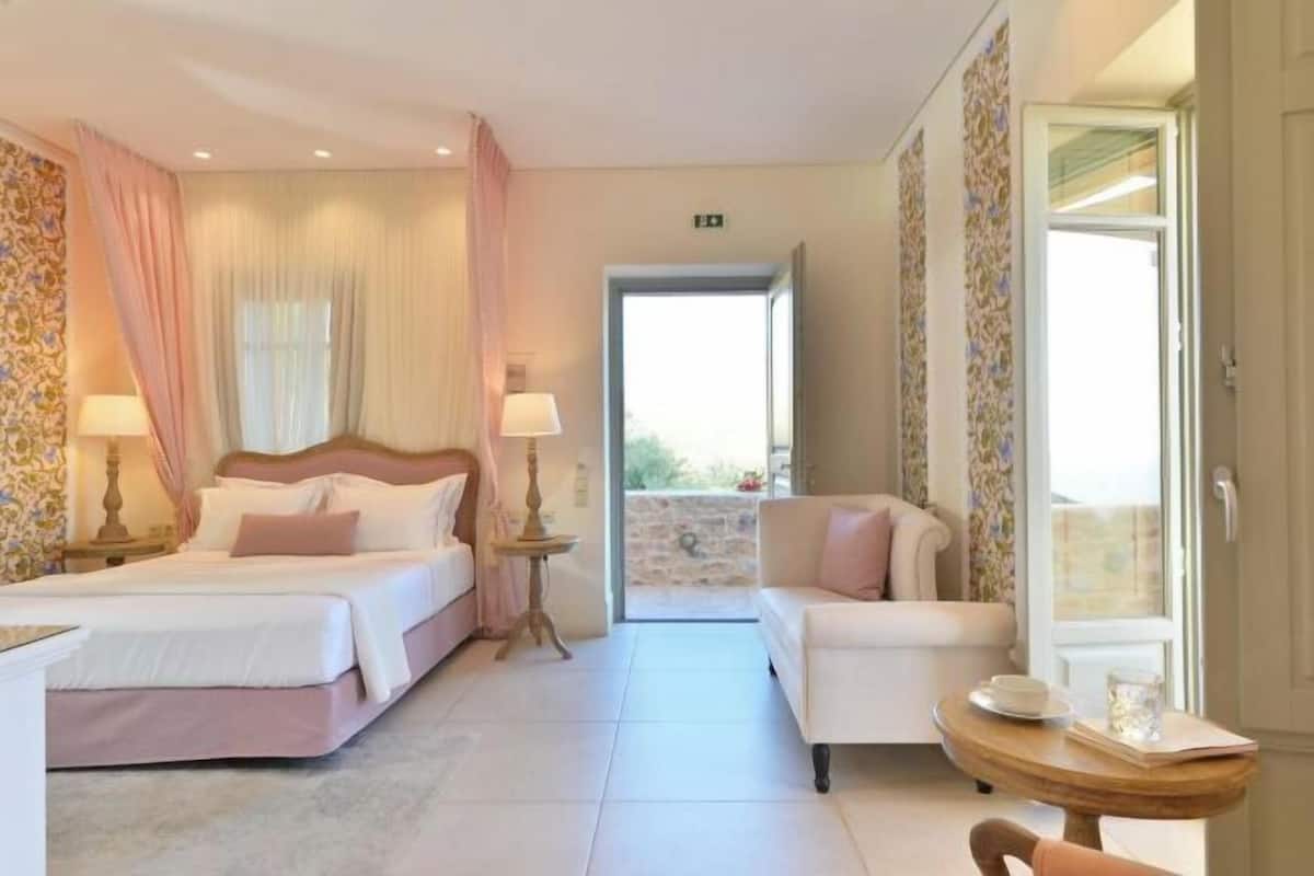 Una habitación de hotel con cama, sofá, una mesita y vistas al exterior.