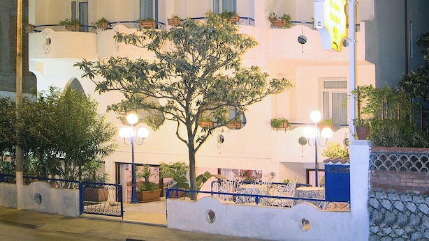 A multi-story hotel with balconies, potted plants, and a sign indicating it is a sports hotel. - Sporting Baia Dependence Villa Athena (Giardini Naxos)