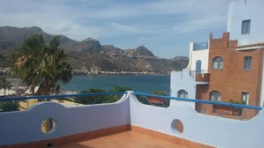 A terrace with a view of a coastal town, a mountain, and a palm tree. - Sporting Baia Dependence Villa Athena (Giardini Naxos)