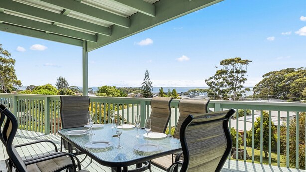 A covered outdoor dining area with a table set for four, overlooking a scenic view. - Daybreak by Experience Jervis Bay (Vincentia)