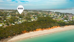 An aerial view of Jervis Bay with a mix of residential areas, dense greenery, and a beach. - Daybreak by Experience Jervis Bay (Vincentia)