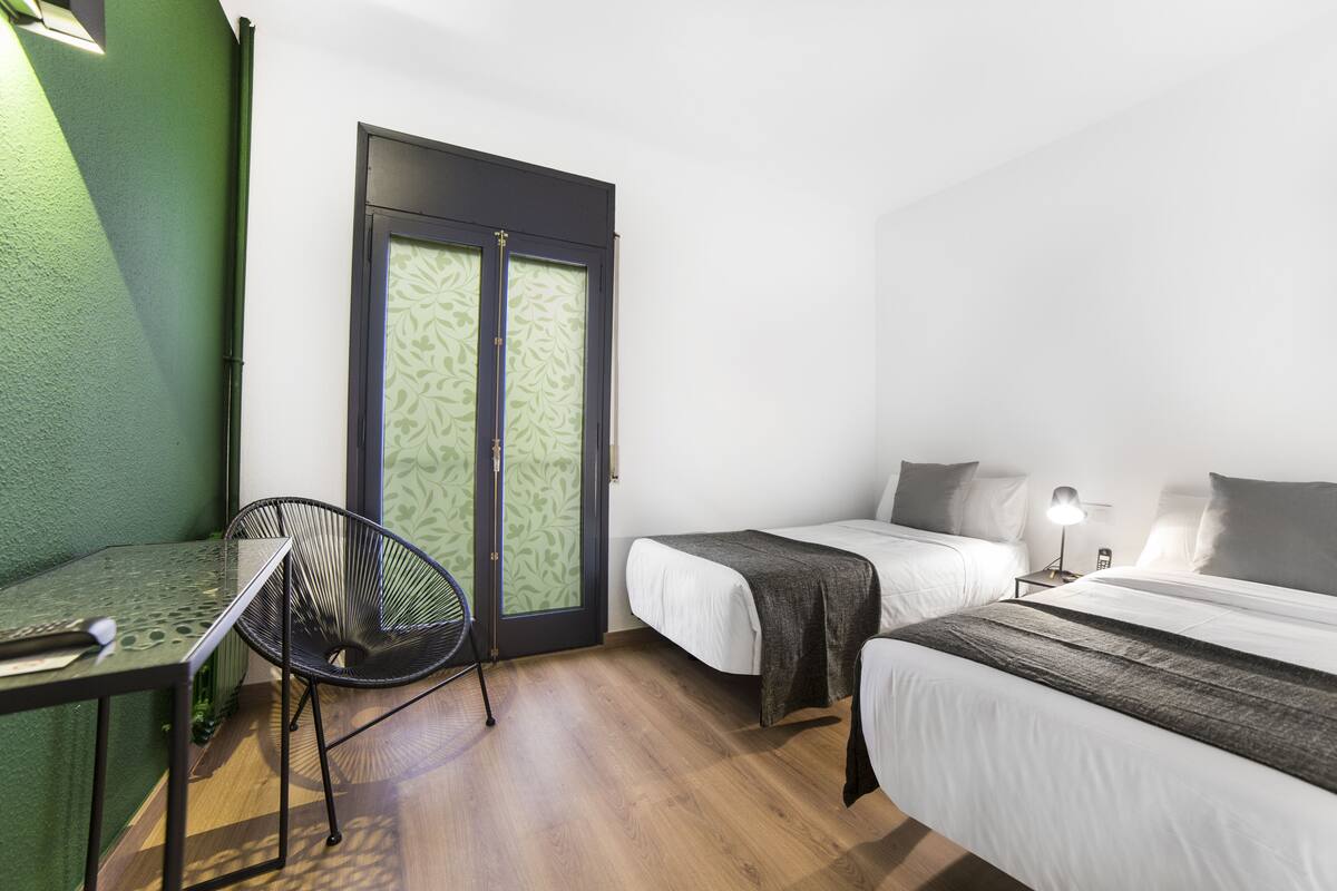 A room with two beds, a chair, a table, and a door with patterned glass.