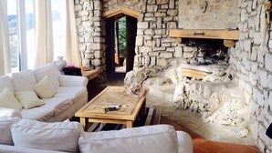 A cozy living room with a stone fireplace, a white sofa, and a wooden coffee table. - Nido del Nibbio (Subiaco)
