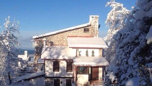 A stone house with a snow-covered roof and a small porch. - Nido del Nibbio (Subiaco)