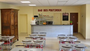 A restaurant interior with a bar area, tables, chairs, and a wooden cabinet.