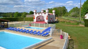 A swimming pool with blue lounge chairs and a castle-like structure in the background.