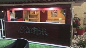 A restaurant named "Splashbar" with a tiled roof, a counter with a glass display, and a red door.
