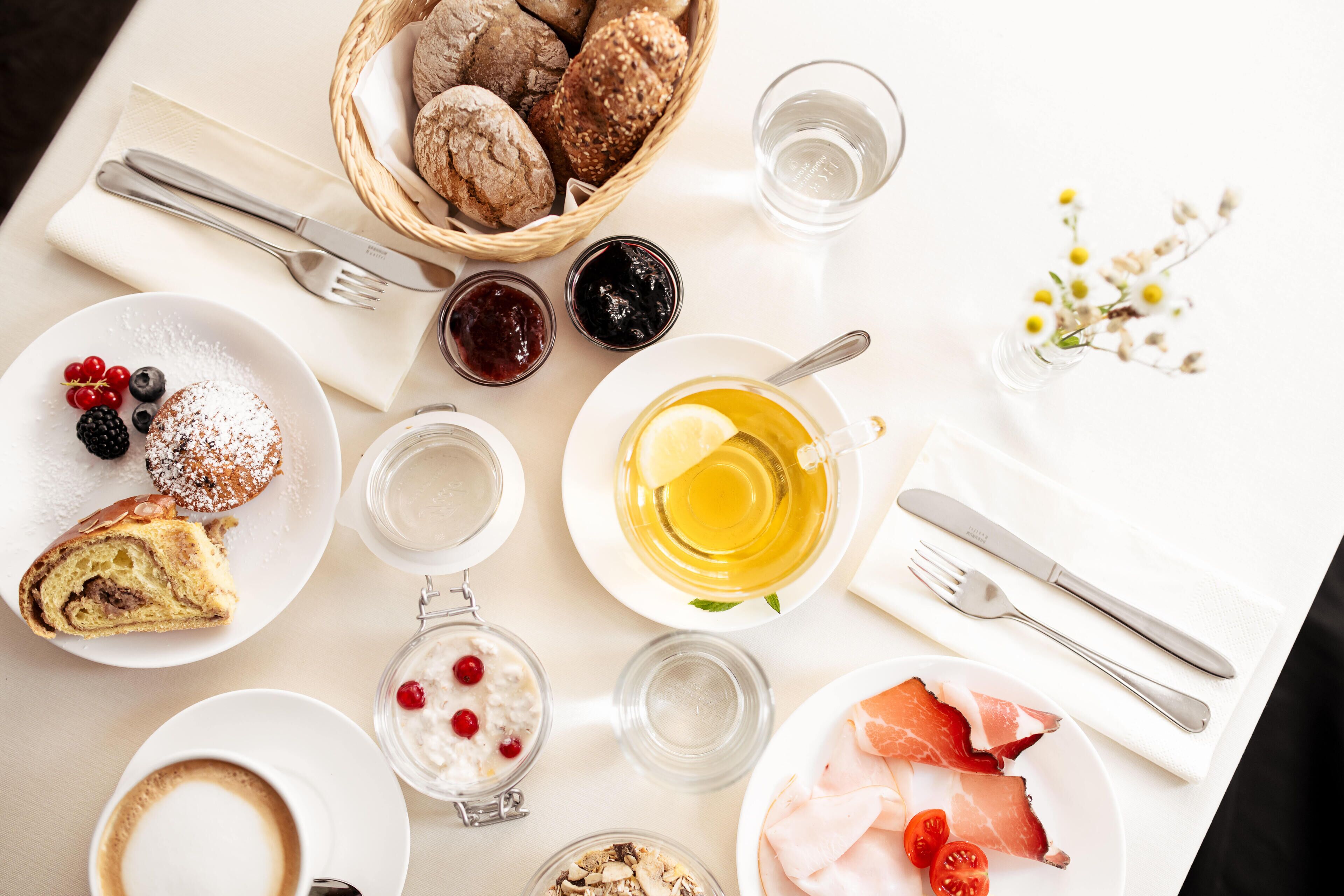 Una mesa de desayuno con diferentes alimentos, como pasteles, frutas y bebidas.