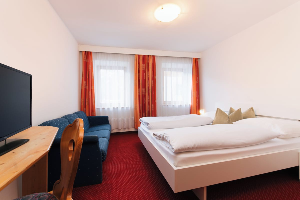 Una habitación de hotel con cama, escritorio, silla y televisor.
