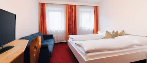 A hotel room with a bed, a desk, a chair, and a television.