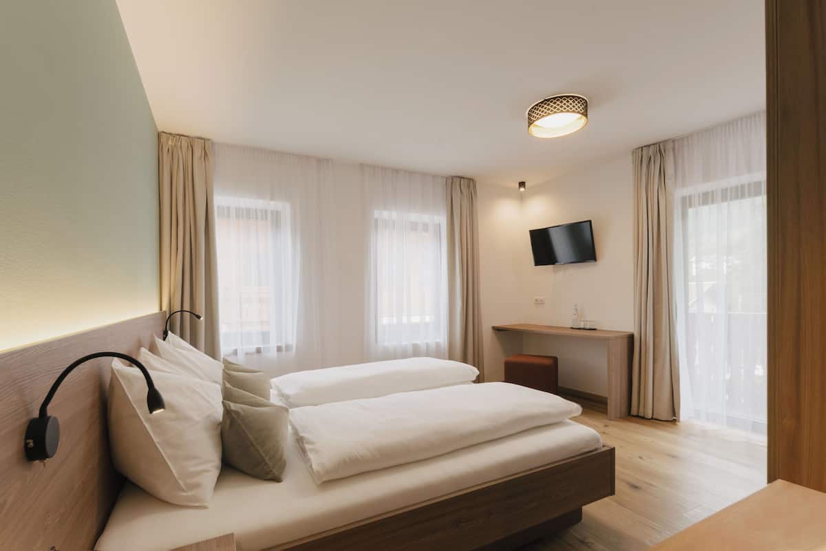 Una habitación de hotel moderna con una cama grande, un escritorio y un televisor.