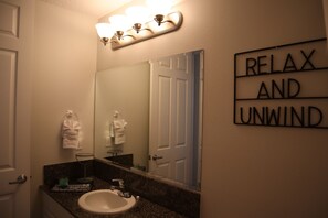 A bathroom with a sink, mirror, and a sign that reads "RELAX AND UNWIND".