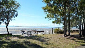 A park with picnic tables and benches overlooking a beach. - San Marco Villa 3 - Burrum Heads - Beachfront - 2BR - Pool (BURRUM HEADS)