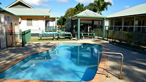 A swimming pool with a safety ladder, surrounded by a fenced area with picnic tables and a covered seating area. - San Marco Villa 3 - Burrum Heads - Beachfront - 2BR - Pool (BURRUM HEADS)