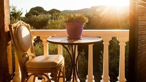 Una silla y una mesa de madera en un balcón con vistas al paisaje y montañas.