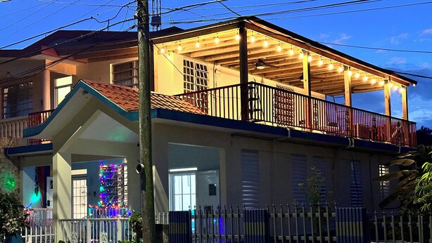 A two-story house with a balcony, a covered porch, and a fenced front yard. - A second story house at less than 5 min walking from beach (Aguada)