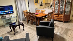 A living room with a TV, wooden dining table, chairs, a glass coffee table, and a cabinet with glass doors. - A second story house at less than 5 min walking from beach (Aguada)