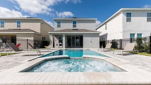 Um edifício residencial moderno com piscina, área de estar externa e céu claro.
