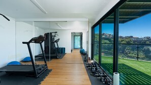 A modern gym with treadmills, weights, and a clear view of a green landscape.