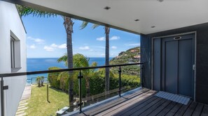 A balcony with a view of the ocean and a mountainous landscape.