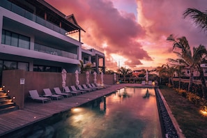 A modern hotel with a pool, lounge chairs, and a sunset view. - Mythic Suites & Villas by MJ Holidays (Grand Gaube)