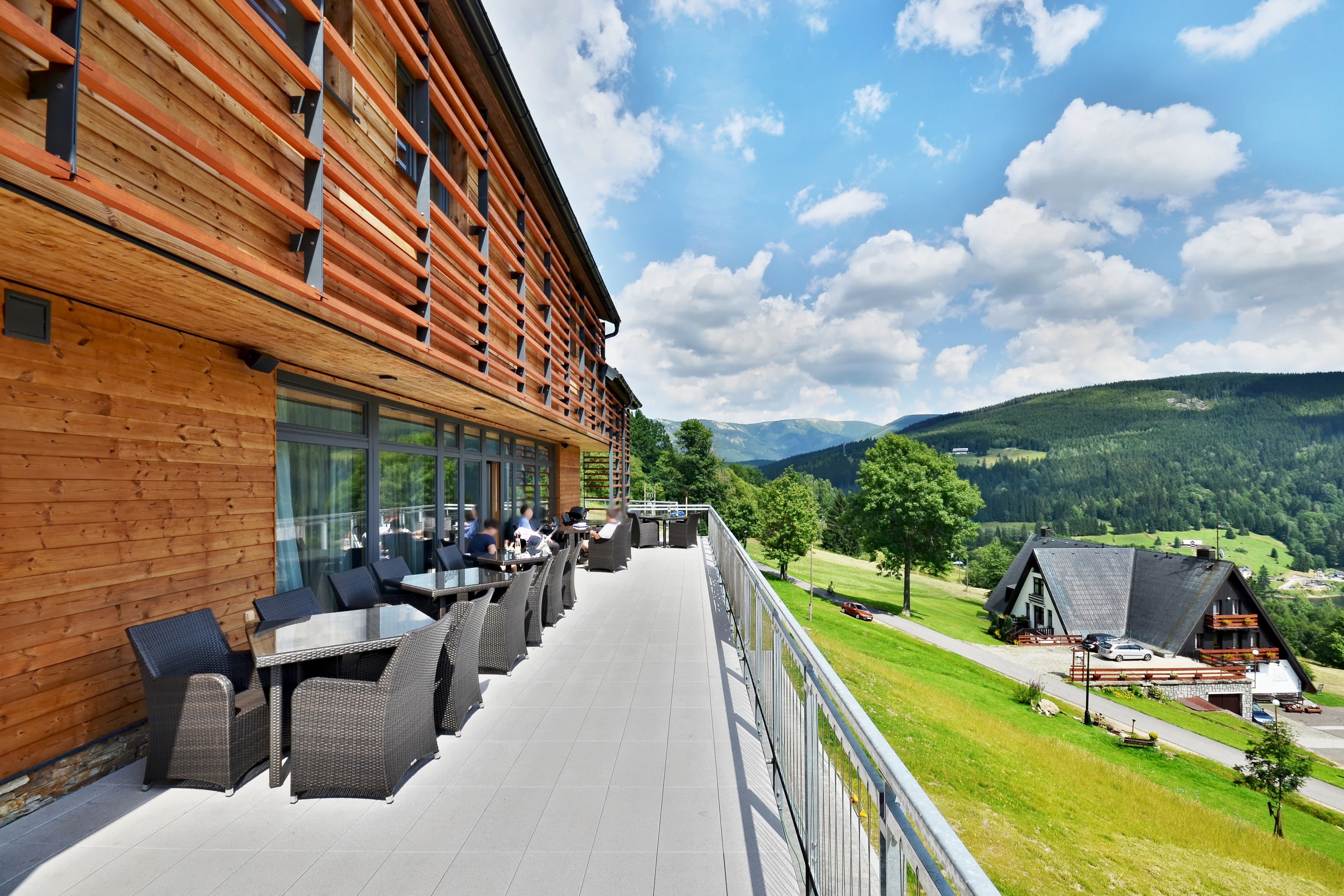 A wooden building with outdoor seating and a view of the countryside.