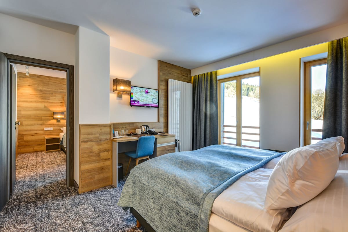 Een hotelkamer met een bed, een bureau, een stoel, een televisie en uitzicht op de omgeving.